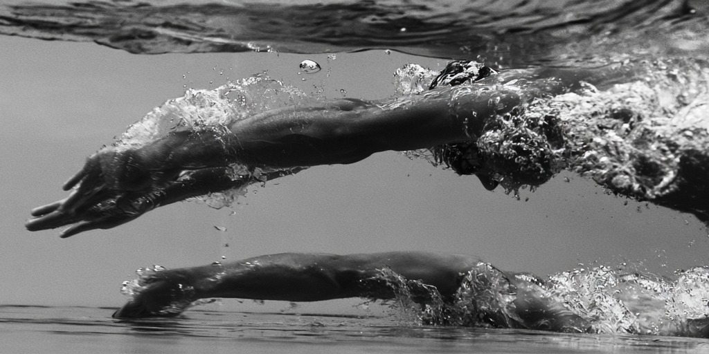 Two underwater views of a swimmer's arm at full extension beneath the surface