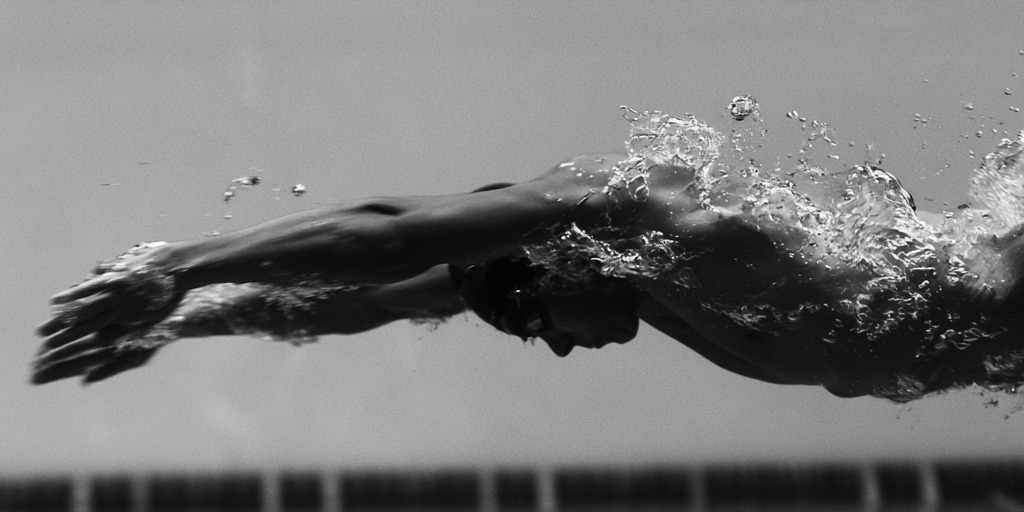 Underwater profile of a swimmer streamlined under the surface, bubbles trailing